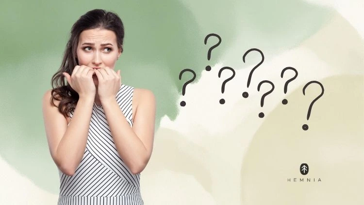 A nervous woman with her hands to her mouth and question marks symbolising uncertainty and stress; logo Hemnia in the bottom right-hand corner